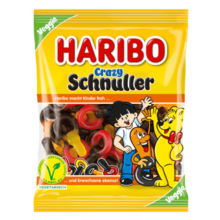 Haribo Crazy Schnuller slikpose fra Købogspar – gul pose med stort rødt HARIBO-logo og teksten ‘Crazy Schnuller’ i blå og sort. På forsiden ses farverige vingummi-sutter i rød, gul, orange og mørk lakridsfarve. Nederst står Haribos kendte figurer: den gule bjørn, et orange vingummimenneske og et barn, der alle smiler og hilser. Posens øverste hjørne er markeret med ‘Veggie’ og vegetarisk V-label, hvilket gør produktet velegnet til vegetarer. Perfekt for kunder der søger Haribo Schnuller, Crazy Schnuller. 